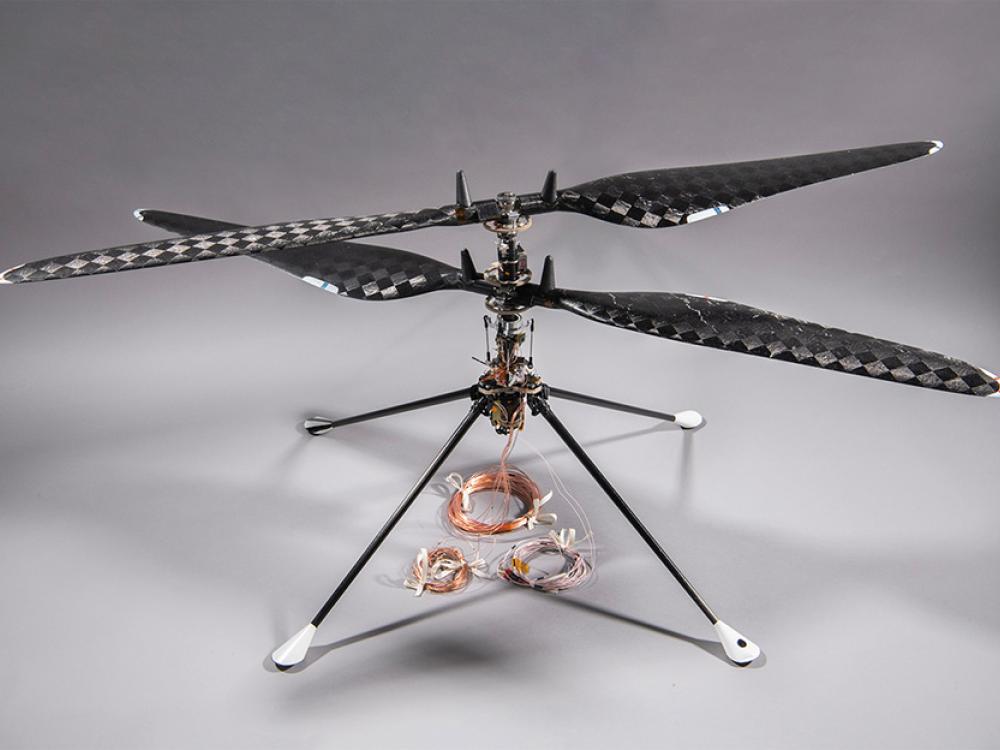 A drone with a simple, spartan chassis has two helicopter blades, one mounted above the other.