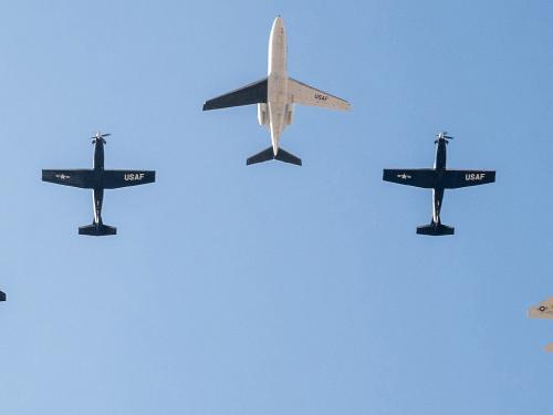 Five Air Force aircraft fly in formation in the cloudless blue sky.