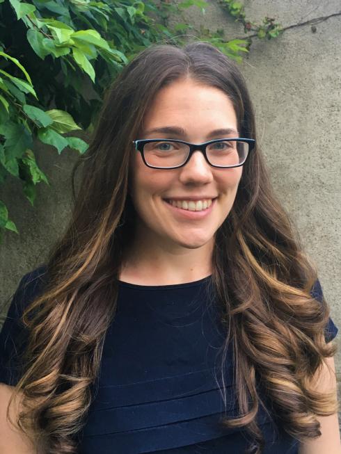 A portrait of a woman with long hair and glasses wearing a blue shirt. 